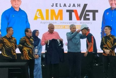 Ahmad Zahid (tengah) memakaikan jaket dan topi kepada ikon AIM TVET sebagai simbolik pelancaran Kelab Kemahiran AIM TVET sempena Jelajah  AIM TVET Peringkat Negeri Perak di Ipoh pada Sabtu.
