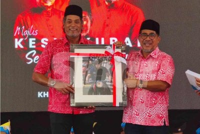 Khairy (kiri) menerima cenderamata yang disampaikan oleh Md Alwi semasa hadir merasmikan Majlis Kesyukuran Sempena Ulang Tahun UMNO Ke-80 di Tapak Rumah UMNO Ketereh, Kota Bharu pada Sabtu. 