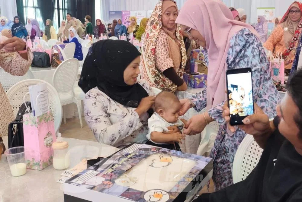 Sabariah menyerahkan bantuan kepada pasangan salah seorang ibu pada program itu.