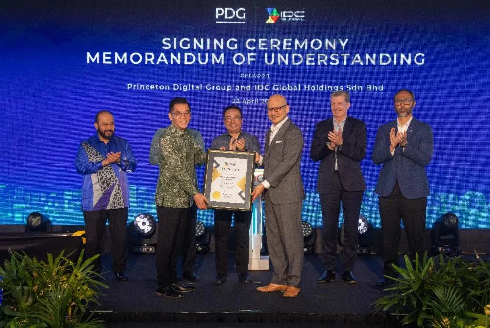 Asher (depan, kanan) menerima sijil pengiktirafan diberikan kepada PDG sebagai pengendali pusat data hiperskala perintis di Malaysia yang bekerjasama menggunakan teknologi penyahkarbon berasaskan graphene CODE , daripada Roger Heng (depan, kiri) sempena majlis pemeteraian MoU antara PDG dan IDC Global Holdings Sdn Bhd di kampus Sedenak, Johor pada 23 April lalu.