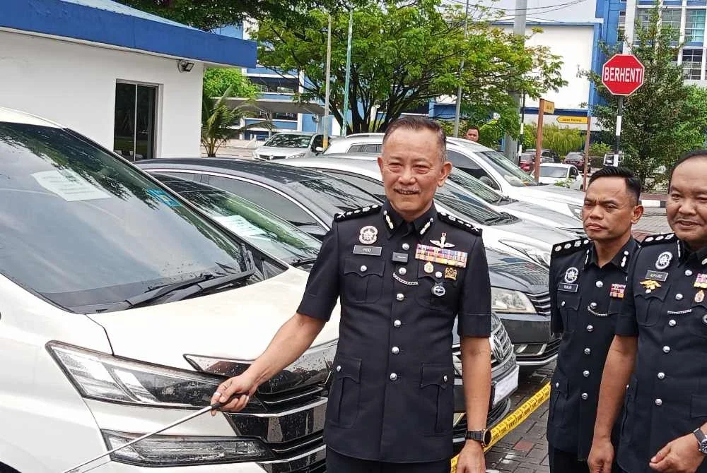 Chuan Huat (kiri) menunjukkan pelbagai jenis kereta yang dirampas daripada sindiket ketika sidang akhbar di IPK Johor pada Isnin.