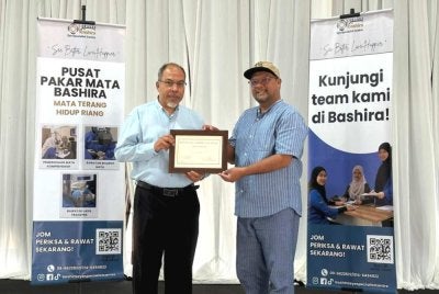 Harmy (kiri) menyerahkan baucar RM200 kepada Timbalan Presiden METRA, Mohd Ishaq Abdillah Ngah sempena program Luncheon Special Talk: Healthy Eye Care for Life di Kuala Terengganu pada Ahad.