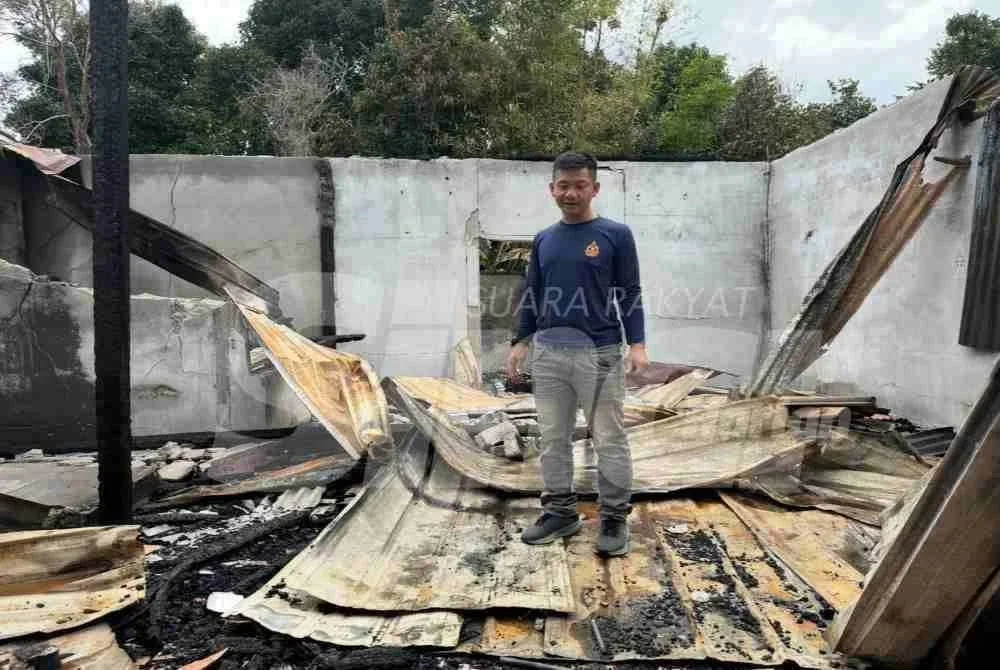 Mohd Alifudin berdiri di dalam rumah terbakar pada Jumaat lalu.