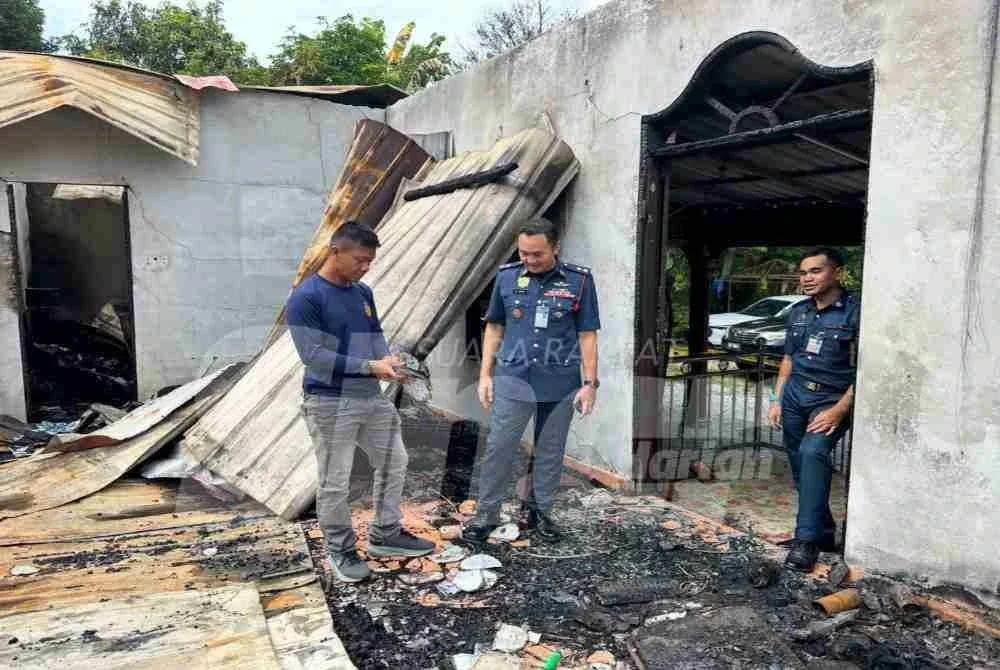 Mohd Alifudin (kiri) melihat kertas-kertas dari buku sekolah anak-anaknya yang terbakar.