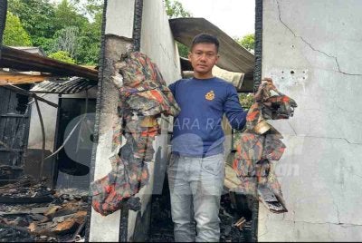 Mohd Alifudin menunjukkan sisa cebisan seragam celoreng yang terbakar.

