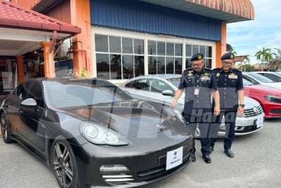 Mohd Misuari (kiri) melihat Porsche Panamera V6 yang disita JPJ Kelantan. Foto: ADILA SHARINNI WAHID