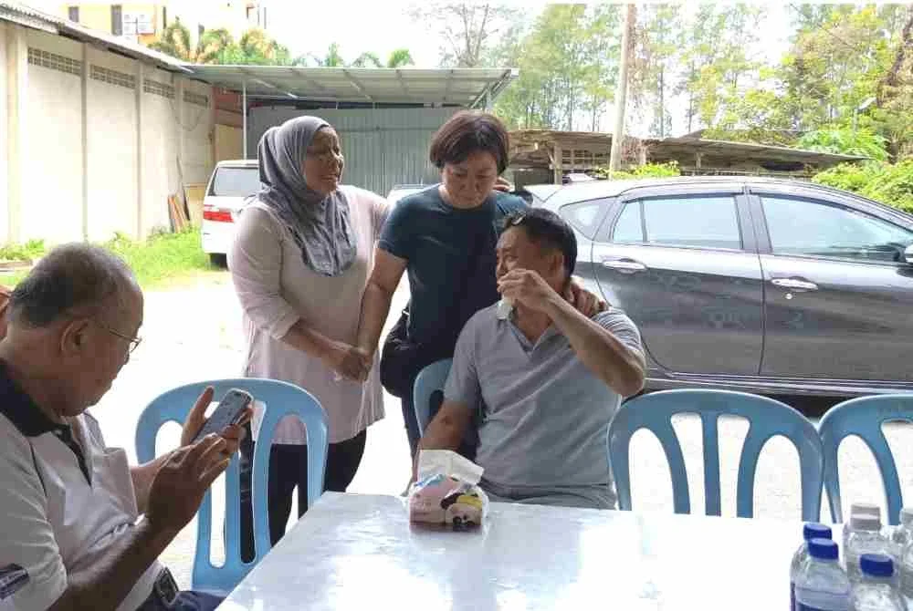 Norharizan (dua dari kiri) bersama ibu dan bapa mendiang Wah Han Keong di rumah upacara pengebumian di Jalan Syed Zain, Kuala Terengganu pada Rabu.