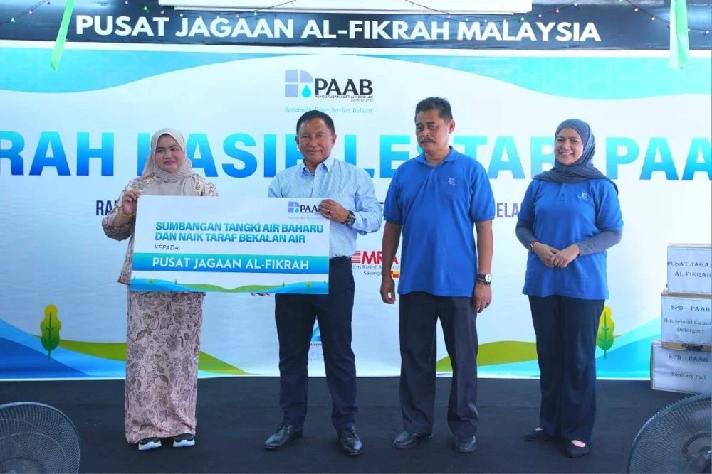 Rozaifee menyerahkan sumbangan kepada Nurul Atikah (kiri) mewakili Pusat Jagaan Al-Fikrah.