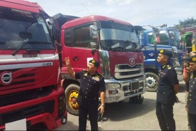 Muhammad Kifli (kiri) menunjukkan pelekat khas yang didapati di sebuah lori.