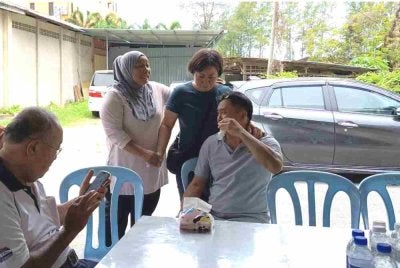 Norharizan (dua dari kiri) bersama ibu dan bapa mendiang Wah Han Keong di rumah upacara pengebumian di Jalan Syed Zain, Kuala Terengganu pada Rabu.