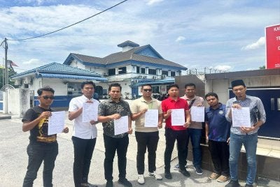 Halim (tiga dari kiri) bersama pimpinan Armada Bersatu Perak menunjukkan salinan laporan polis yang dibuat terhadap Tony di hadapan pintu masuk IPD Ipoh di sini pada Rabu.