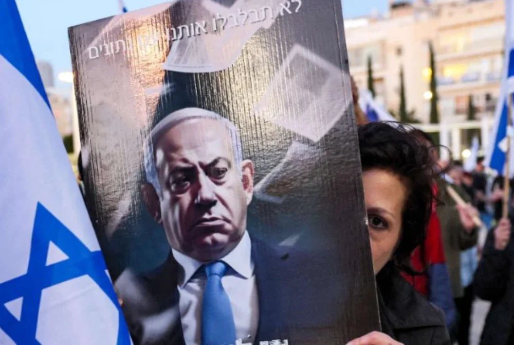Penunjuk perasaan memegang plakad yang tertera slogan menuntut pengunduran Netanyahu. - Agensi