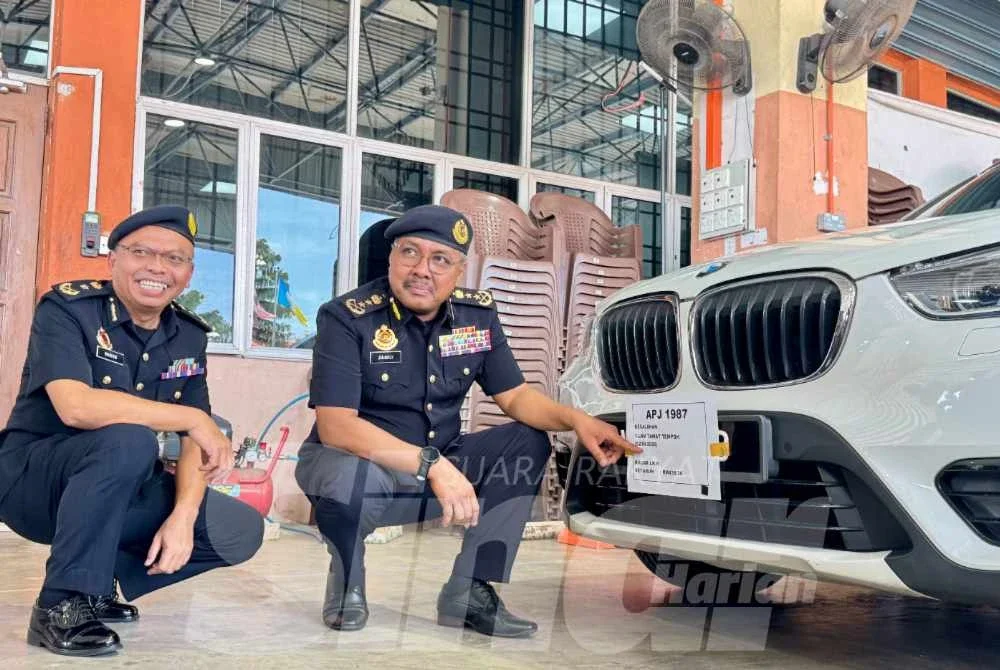 Zulkifly (kanan) menunjukkan sebuah kereta BMX yang disita kerana gagal memperbaharui cukai jalan.