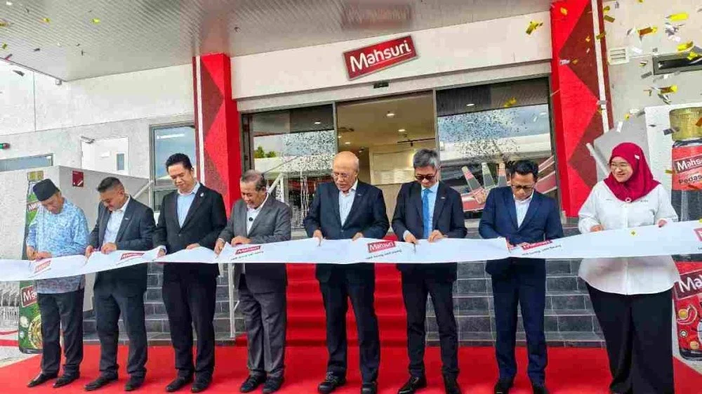Aminuddin (empat dari kiri) dan Mohd Roslan (empat dari kanan) memotong 'reben' sebagai simbolik perasmian Kilang Mahsuri Food Sdn Bhd di Bandar Baru Enstek pada Jumaat.