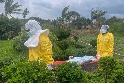 Staf perubatan lengkap memakai sut peralatan perlindungan diri (PPE) membawa pesakit disyaki ke sebuah hospital di Rwampara.
