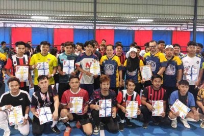 Ahmad (tengah) menyerahkan sijil kepada peserta Liga Sukan Komuniti di Stadium Futsal Bandar Baru Pontian pada Sabtu.