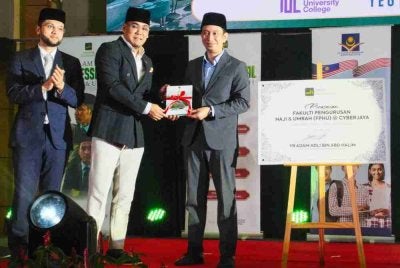 Pengarah Urusan YEG M Sdn Bhd, Hasan Ithnin (kiri) menyampaikan cenderahati kepada Adam Adli selepas melancarkan Fakulti Pengurusan Haji dan Umrah YEG@ Cyberjaya pada Sabtu.