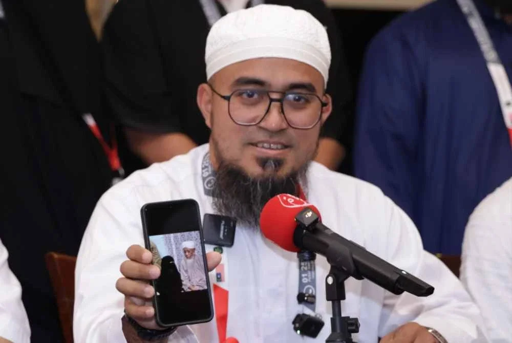 Muhammad Huzair menunjukkan gambar kedua ibu bapanya. 