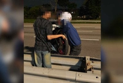 Antara cubaan mengangkat motosikal melintasi pembahagi jalan di Lebuhraya NKVE, Shah Alam pada Ahad. Foto: Polis Selangor