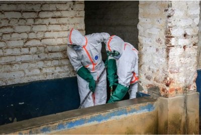 Pekerja kesihatan lengkap memakai sut perlindungan diri (PPE) melakukan prosedur nyahjangkit di ruang pengasingan pesakit Ebola di Mongbwalu. - Foto AFP