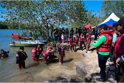 Pasukan penyelamat mengangkat mayat mangsa lemas ketika mandi bersama empat rakan mereka di Sungai Beril. Foto Bernama