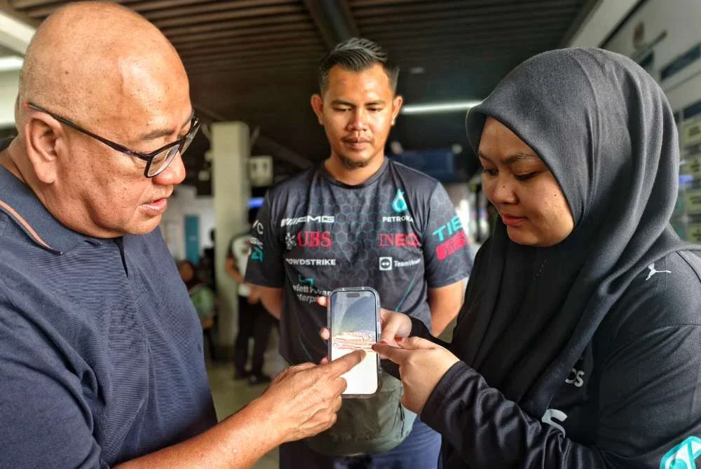 Mohd Faizal melihat gambar buaya Sungai Linggi ditunjukkan oleh Nur Syuhadah.