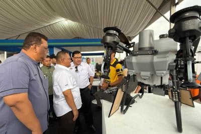 Yuhaizad (tengah) dan Mohd Haniff (kanan) meninjau dron yang digunakan untuk pertanian.
