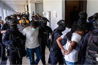 Sebahagian daripada 11 lelaki diiringi anggota polis ketika dihadapkan ke Mahkamah Sesyen Kuala Lumpur pada Isnin atas pertuduhan menjadi anggota kumpulan jenayah terancang dikenali sebagai 'Geng RT6' sejak enam tahun lalu. Foto Bernama