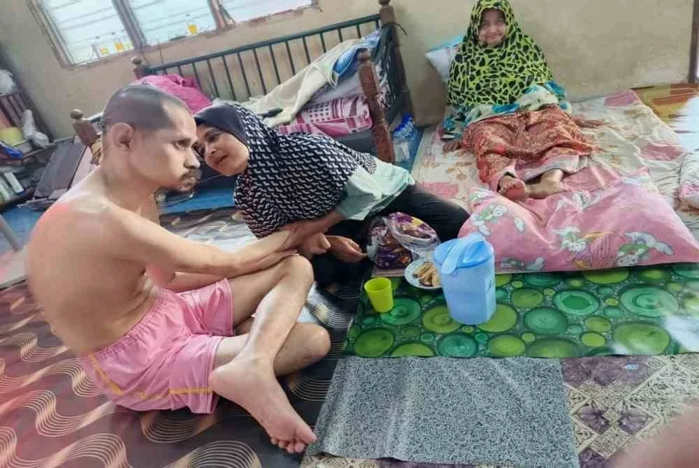 Rosnani menyuap adiknya, Mohamad Saffari makan di samping ibunya, Robiah ketika ditemui di kediaman mereka di Batu Buruk, Kuala Terengganu.