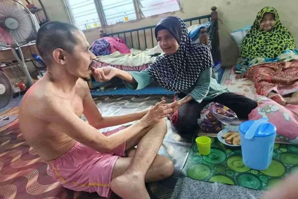 Rosnani menyuap adiknya, Mohamad Saffari makan di samping ibunya, Robiah ketika ditemui di kediaman mereka di Batu Buruk, Kuala Terengganu.