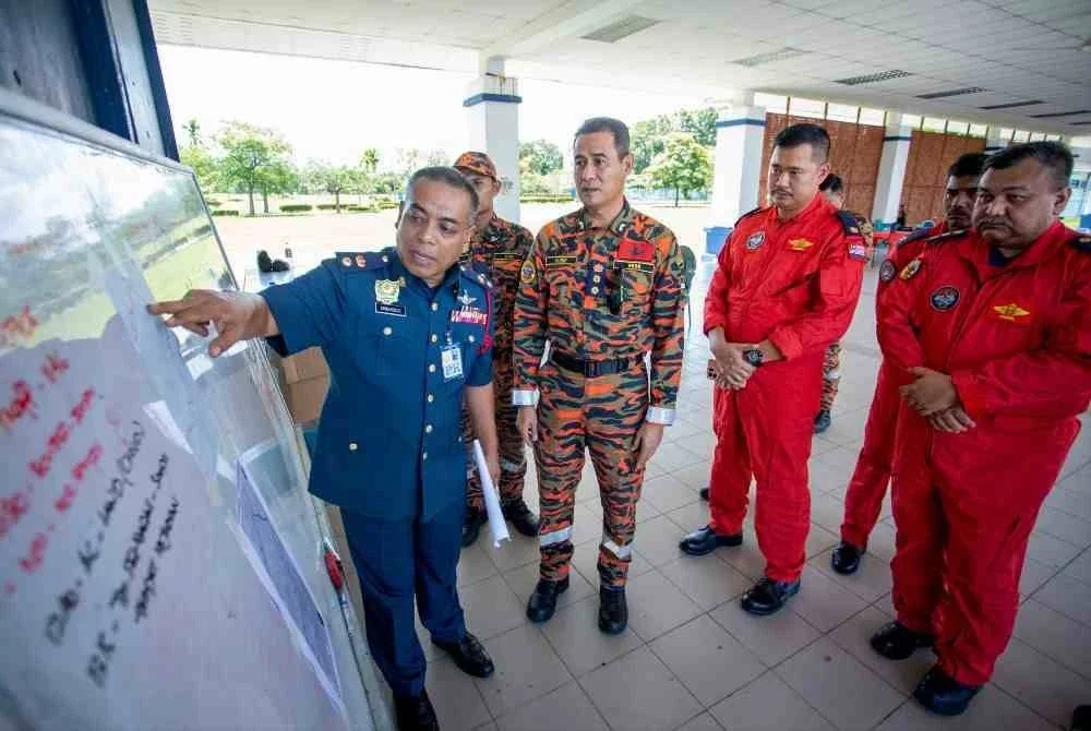 Timbalan Pengarah Jabatan Bomba dan Penyelamat Malaysia (JBPM) Perak Yusri Mohd Yusoff @ Hashim (tiga, kiri) mendengar penerangan daripada Penolong Pengarah Bahagian Operasi Jabatan Bomba dan Penyelamat Malaysia (JBPM) Perak Sabarozi Nor Ahmad (kiri) berkaitan operasi mencari dan menyelamat (SAR) mangsa Jaslinda Saludin, 49, yang dilaporkan hilang ketika menyertai pendakian di Gunung Batu Putih pada Ahad lepas, di Kem Batalion 3 Pasukan Gerakan Am (PGA), Bidor hari ini. Foto Bernama.