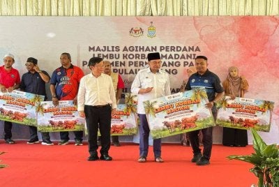 Anwar menyerahkan kad replika penyerahan lembu kepada penerima.