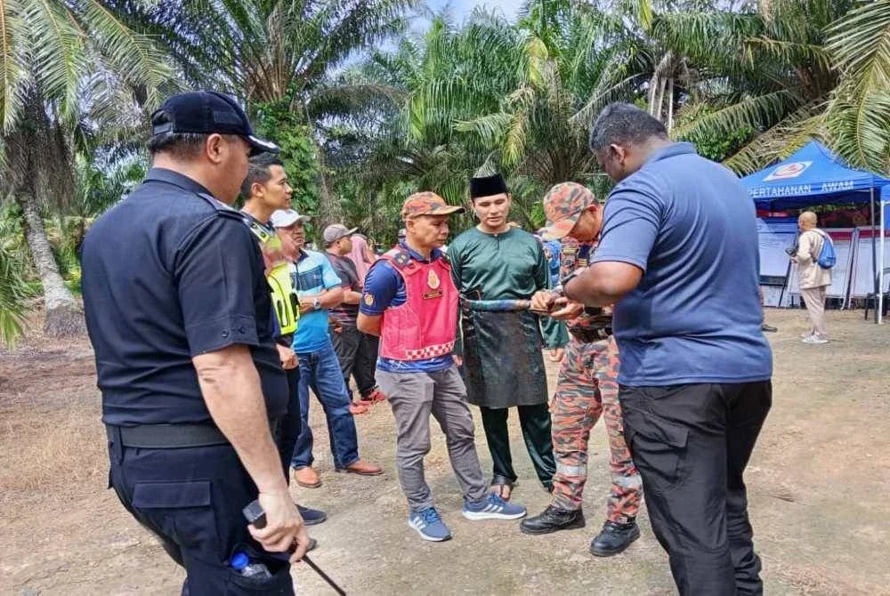 Hadzrat Hussien (tiga dari kanan) berbincang dengan anggota SAR di pos kawalan di Kampung Medan Sari Pontian.