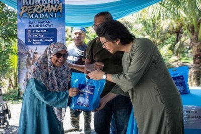 Muhammad Kamil (kanan) menyerahkan daging korban kepada penerima sempena Majlis Program Korban Perdana Madani di Kampung Ribu, Padang Rengas pada Rabu.