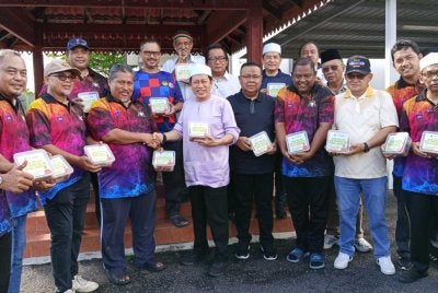 Ahmad (tengah) menyerahkan agihan daging korban di Kompleks Penghulu Mukim Benut pada Khamis.