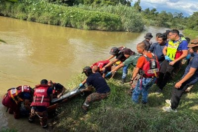 Anggota bomba mengangkat mayat mangsa yang ditemukan tidak jauh dari lokasi jatuh. 