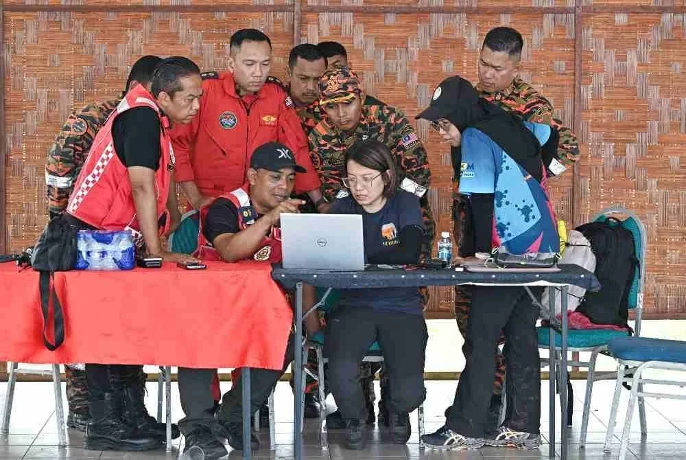 Penolong Pengarah Operasi Jabatan Bomba dan Penyelamat Malaysia (JBPM) Perak, Sabarodzi Nor Ahmad (dua kiri), mendengar penerangan daripada wakil Persatuan Badan Bukan Kerajaan (NGO) PELINDUNG, Liang Neo Song Wee (dua kanan), mengenai rakaman ‘camera trap’ yang dipasang di kawasan dipercayai lokasi mangsa pendaki wanita yang hilang, Jaslinda Saludin, 49, ketika ditemui di Pusat Kawalan Hadapan (PKH) Bomba di Batalion 3 PGA, Bidor, hari ini.Foto Bernama.