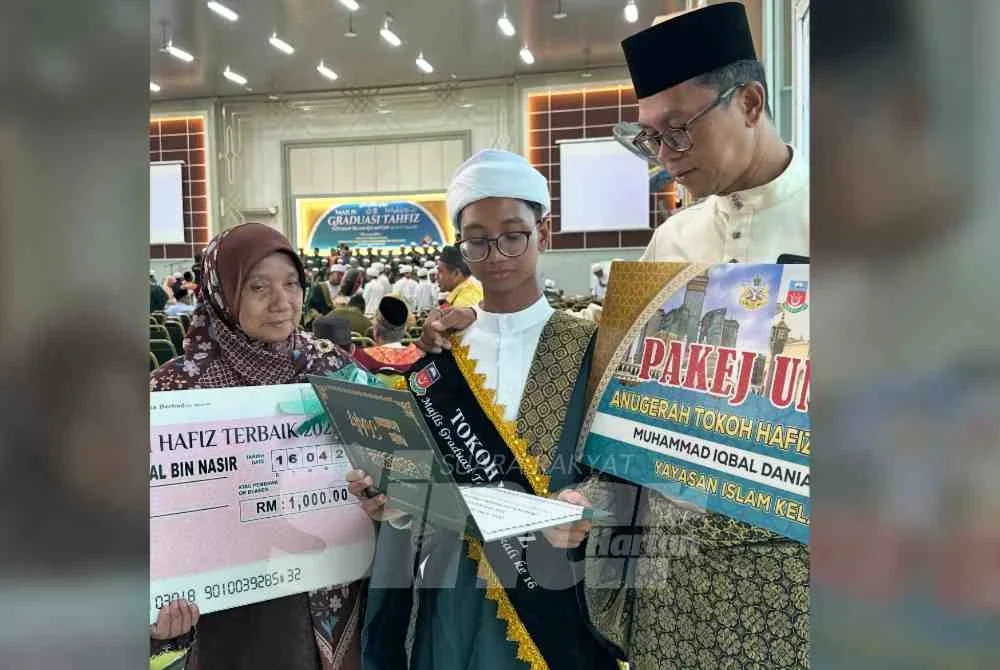 Muhammad Iqbal Danial (tengah) menunjukkan sijil sebagai tokoh tahfiz yang diperoleh kepada ibu bapanya.