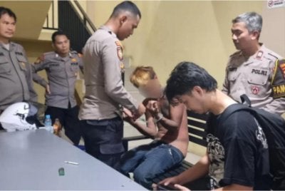 Suspek (tengah) ketika ditahan polis tempatan.- Foto.sapos.co.id.