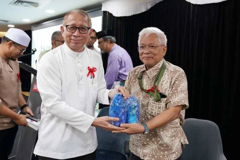 Kamal Nasharuddin menyampaikan cenderahati kepada Hussamuddin yang menjadi tuan rumah Himpunan Anok Beranok di Karangkraf pada Isnin. Foto Rosli Talib