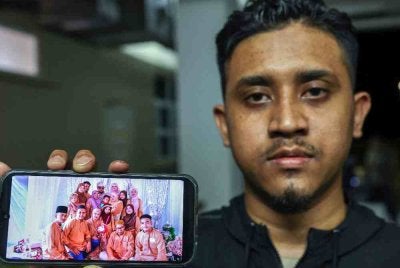 Saudara terdekat, Muhammad Syahir Mohd Rofi, 28, menunjukkan gambar perkahwinan, Mohd Aiman (belakang, tengah) dan Nor Azlina (belakang, kanan). Foto: Bernama
