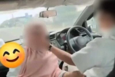 Tangkap layar rakaman video kes tular yang memaparkan seorang wanita duduk menghadap pemandu kereta.