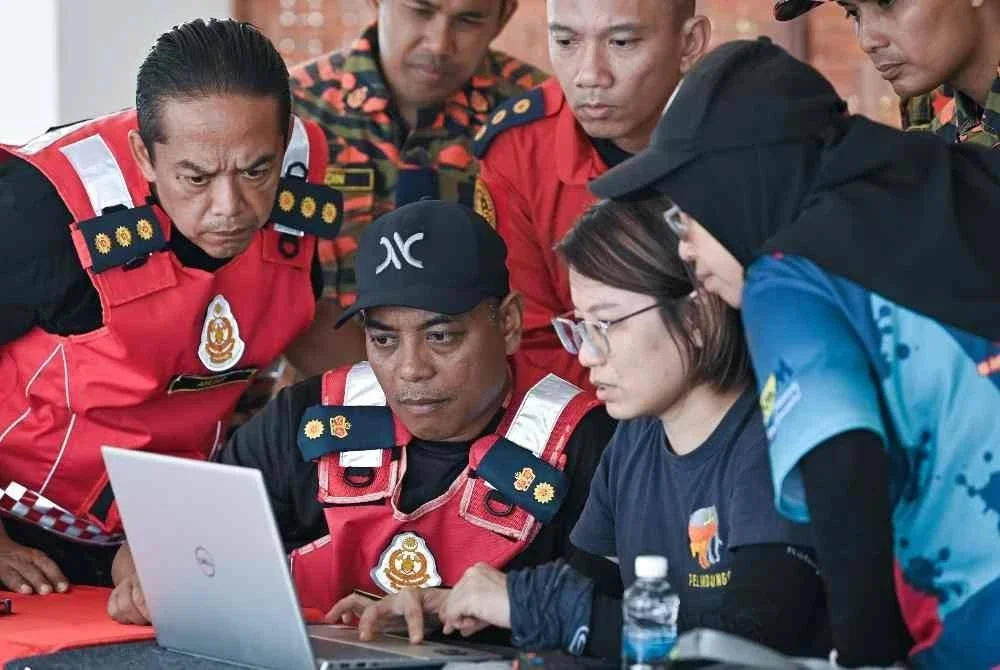 Penolong Pengarah Operasi Jabatan Bomba dan Penyelamat Malaysia (JBPM) Perak, Sabarodzi Nor Ahmad (dua kiri), mendengar penerangan daripada wakil Persatuan Badan Bukan Kerajaan (NGO) PELINDUNG, Liang Neo Song Wee (dua kanan), mengenai rakaman ‘camera trap’ yang dipasang di kawasan dipercayai lokasi mangsa pendaki wanita yang hilang, Jaslinda Saludin, 49, ketika ditemui di Pusat Kawalan Hadapan (PKH) Bomba di Batalion 3 PGA, Bidor. Foto Bernama.