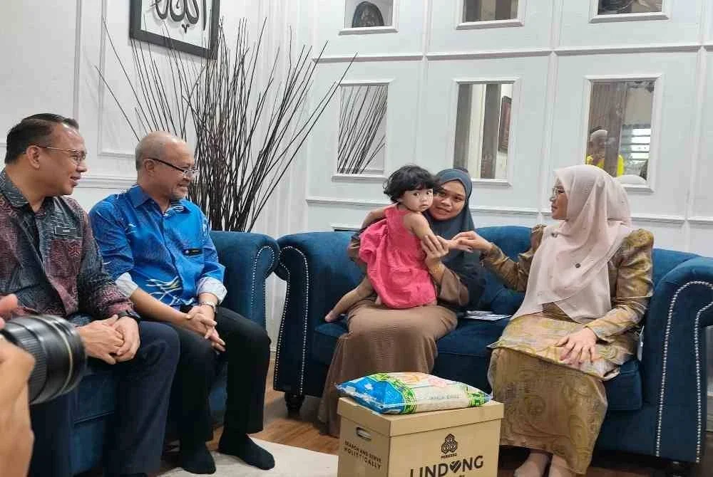 Sabariah (kanan) beramah mesra dengan anak sulung arwah pada Ziarah Prihatin Pertubuhan Keselamatan Sosial (PERKESO) kediaman keluarganya di Bukit Setongkol di sini pada Khamis. Foto Sinar Harian.