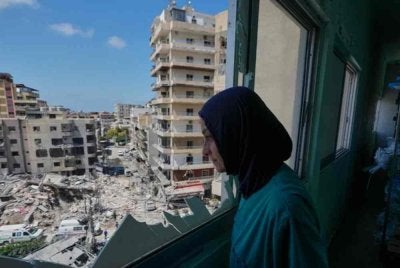 Seorang jururawat melihat melalui tingkap pecah di Hospital Jabal Amel ke arah sebuah bangunan yang musnah akibat serangan udara Israel di bandar pelabuhan selatan Tyre, Lubnan. Foto AP