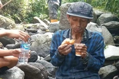Anggota penyelamat berkongsi makanan dengan mangsa sebelum dibawa turun dari gunung itu. - FOTO: Agensi