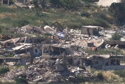 skar Zionis bertindak biadab memacakkan bendera Israel di atas struktur yang musnah dibedil di selatan Beirut. Foto AFP