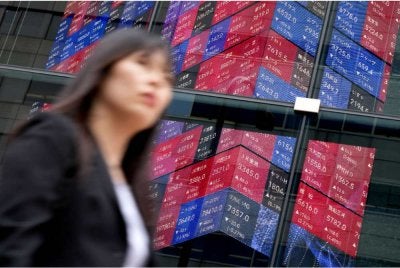 Seorang wanita berjalan melepasi papan paparan elektronik yang memaparkan pergerakan indeks saham Nikkei 225 di luar Tokyo Stock Exchange di Tokyo pada 5 Jun 2026. Pasaran saham Jepun susut susulan tekanan jualan dalam sektor teknologi dan kebimbangan pelabur terhadap prospek industri kecerdasan buatan (AI). Foto AFP
