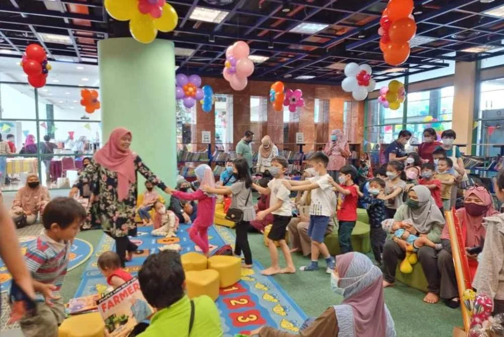 Suraya (berdiri, kiri) sebagai pencerita berjaya menarik minat kanak-kanak untuk membaca buku.