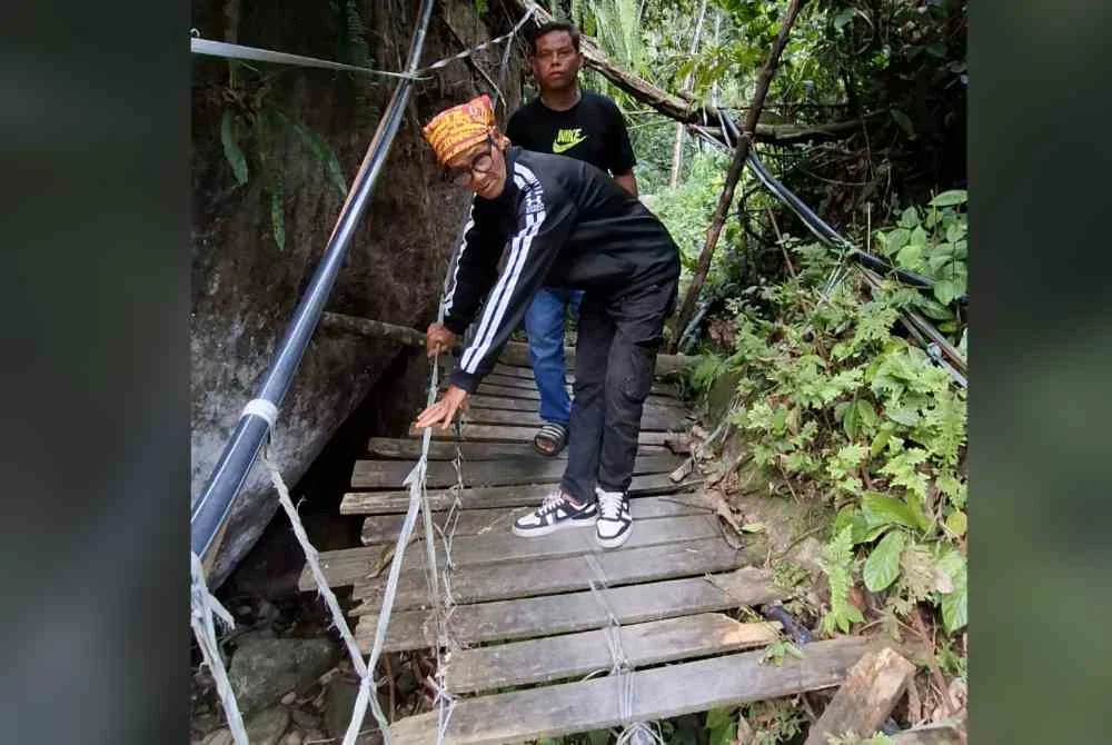 Nazri (hadapan) bersama Bah Roslan menunjukkan keadaan Jaslinda ketika ditemui berjalan seorang diri di atas jambatan di Kampung Lubuk Gaharu dekat Pos Musoh pada Sabtu.